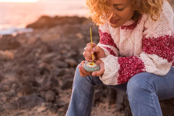 成年妇女在户外的休闲活动中画了一块带有曼陀罗图案的石头 快乐的女性喜欢刷子和颜色 喜欢在石头上创作艺术 夕阳西下 — 图库照片