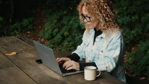 现代女性在森林公园的桌子边使用笔记本电脑 — 图库视频影像