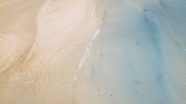Mavi temiz deniz suyuyla kumsal ve kumsalın dikey görüntüsü. Dalgalı ve okyanuslu tropik hava manzarası. Deniz manzarası ve inanılmaz seyahat yeri konsepti. Yaz tatili