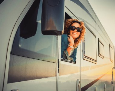 Gezgin neşeli ve mutlu ifade, modern karavan kamyonetinin vitrininin dışındaki güzel genç kadın. Seyahat ve yaz tatili kavramı