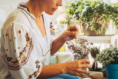 Yakından bak. Yetişkin güzel bayan terasta bedava bitki ve bahçe bakımı yapıyor. Kadınlarla ve bahçe işleriyle uğraşan insanlar. Doğayı ve çiçekleri seven genç bayan rahatlıyor.