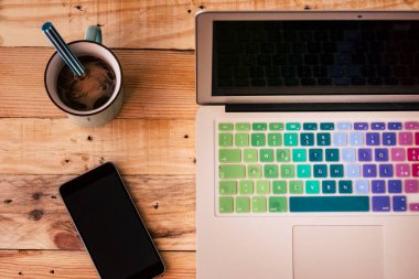 Telefon kahvesi ve dizüstü bilgisayarı olan bir masa. Ofisteki ahşap masada çalışma yeri. Ev ve iş dünyası online konsepti. Akıllı çalışma ve bağlantı. Modern yaşam tarzı işi