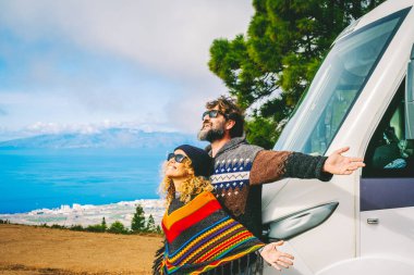 Minibüs hayatı ve seyahat konsepti. Erkek ve kadın, doğaya yeni geldikleri için heyecanlı. Yeni modern karavan kampçılarına karşı kollarını açıyorlar. Karavanlı bedava kamp alanı. Şebekeden uzakta yaşayan insanlar