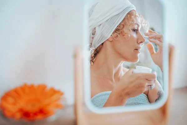 漂亮的年轻成年女性在家里照顾她的皮肤 女人反映在一面镜子中的美 休闲活动 老化产品的护肤和护肤霜 天然使用皮肤化妆品的人 — 图库照片
