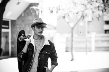 Şehirde gezen modern kaykaylı bir gencin siyah beyaz portresi.