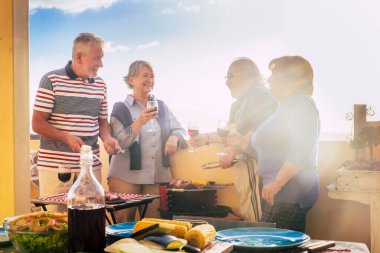 Bir grup yaşlı erkek ve kadın barbekü ve eğlence etkinliğinde birlikte yemek yemekten hoşlanırlar. Olgun çiftler evlerinde yiyecek ve içeceklerle arkadaşlıkta eğlenirler. İnsanlar ve tatil günü kavramı
