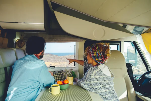 Kamp evinin pencerelerinin dışındaki doğa manzarasına hayran olan bir çiftin arka görüntüsü. Minibüs yaşam tarzı ve seyahat turistleri boş zaman aktiviteleri. Yaz tatilinde bir kadın ve bir erkek.