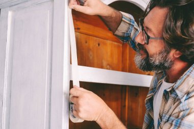 İnsanlar ve hobileri ev konsepti eğlence aktivitelerinde çalışıyor. Yetişkin bir adam eski bir mobilya üzerinde çalışıyor, yenileniyor ve restore ediliyor. Sürdürülebilirlik ve dairesel ekonomi için el yapımı erkekler
