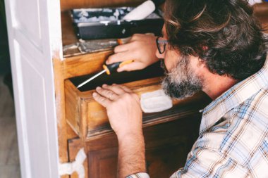 İnsanlar ve hobileri ev konsepti eğlence aktivitelerinde çalışıyor. Yetişkin sakallı bir adam eski mobilyaları yeniliyor ve restore ediyor. Sürdürülebilirlik ve dairesel ekonomi için el yapımı erkekler