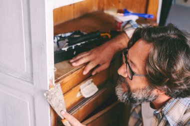İnsanlar ve hobileri ev konsepti eğlence aktivitelerinde çalışıyor. Yetişkin bir adam eski bir mobilya üzerinde çalışıyor, yenileniyor ve restore ediliyor. Sürdürülebilirlik ve dairesel ekonomi için el yapımı erkekler