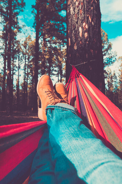 Legs and hammock relax leisure activity with forest woods and sky in background - people enjoy environment and alternative free lifestyle enjoying nature and alternative vacation or weekend alone