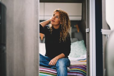 Sevimli, genç, yetişkin bir kadın modern bir karavan karavanının içinde yatak odasında dinleniyor. Minibüs hayatı ve göçebe yaşam tarzı insanları. Kiralık araçla tatil tatili. Bağımsızlık