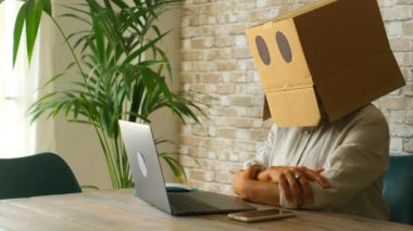 Kimlik ve şifre kurtarma sorunları internette bilgisayar ve web sayfalarıyla çalışıyor. İş yerindeki insanların kafalarında karton kutu var. Ofiste dizüstü bilgisayarı olan depresyonda bir işçi.