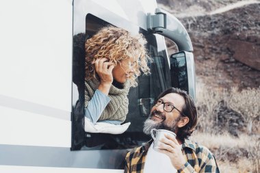 Bir adam ve bir kadın gülümsüyor ve karavan nakliye aracı kullanıyor. Tatilin ve eğlencenin tadını çıkaran bir çift. Karavan penceresinin dışındaki kadın kahve içen bir erkekle konuşuyor. Özgürlükten uzak yaşam