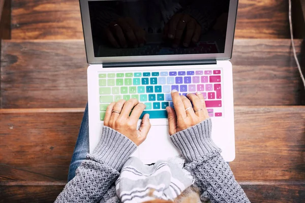 Above view of woman hands writing on computer keyboard. People and laptop use for work or leisure activity. Female enjoying leisure at home. Concept of free and alternative home office job lifestyle