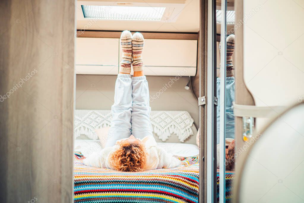 Healthy traveler woman doing stretching and workout exercises inside a camp van bedroom getting up the legs. Alternative van life off grid lifestyle people. Female laying on bed having fun