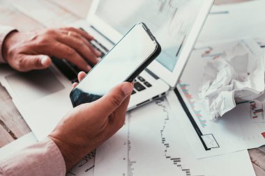 Cep telefonu ve dizüstü bilgisayarla erkek ellerini kapat. Çizelgelerle çalışan insanlar. Borsa konsept işi. Resepsiyonda bir iş. Çevrimiçi bağlantı ve iletişim