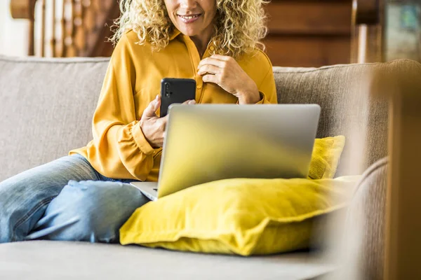 Home leisure activity and technology connection. Woman relaxing on the sofa and use phone and laptop together. Female people with cellular. Communication and social media concept