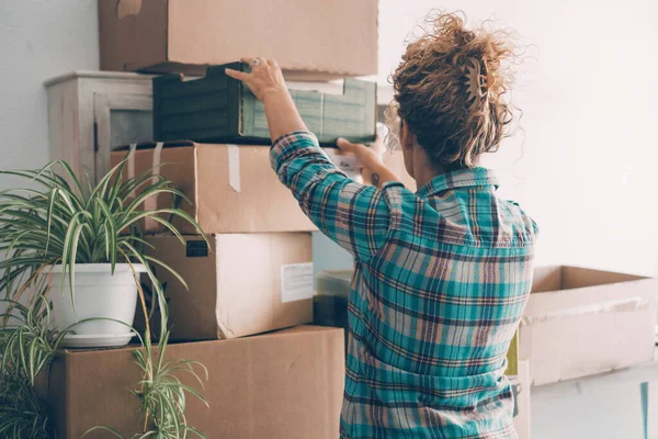 Back view of young woman unpacking after moving to a new home.. Concept of cardboards boxes and work to move and change house. New life concept. Loan and mortgage economy. Independence lady leisure