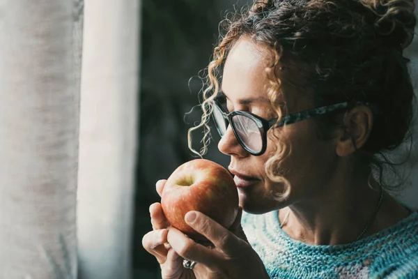 一个女人拿着一个苹果 看着窗外的家的侧面肖像 健康食品 生活方式和水果的概念 有识之士在室内休闲活动中 中年妇女 — 图库照片