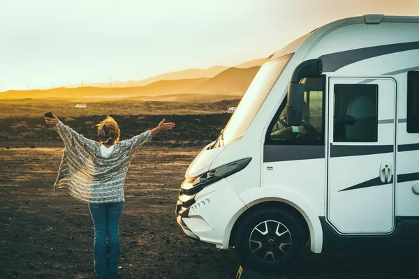 Woman viewed from back enjoy happy her destination in camp van life travel. Back view of female people opening arms and enjoy sunset landscape and freedom. Independence and alternative home vehicle