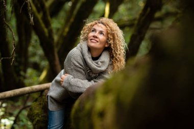 Portrait of smiling and happy woman sitting horseback of a trunk tree in a green beautiful forest woods. Concept of people and environment. Travel tourist lifestyle. Save nature. Beautiful outdoors
