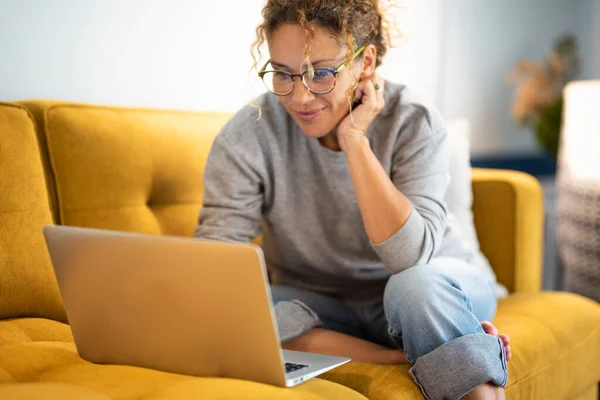Nainen Istuu Keltaisella Sohvalla Kannettavan Tietokoneen Internet Yhteyden Hymyn Avulla — kuvapankkivalokuva
