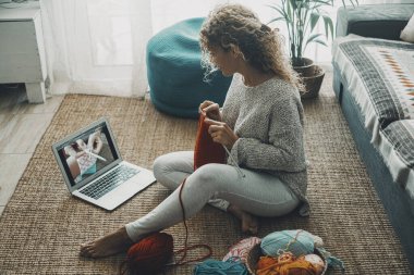Woman at home doing knit work for hobby and leisure activity alone watching tutorial online on internet channel. Concept of people and diy work indoor. People and online content creator job ideas