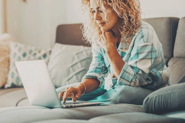 Female Smiles Uses Laptop Sitting Sofa People Enjoying Online Activity – stockfoto