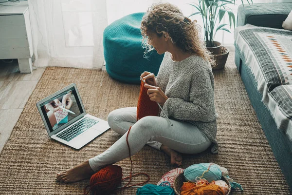 Woman at home doing knit work for hobby and leisure activity alone watching tutorial online on internet channel. Concept of people and diy work indoor. People and online content creator job ideas
