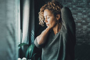 Young mature woman touching his neck for back pain and stretching arms. Concept of healthy and body condition people Female massaging his back for pain and closing eyes to relax. Concept of bad posture