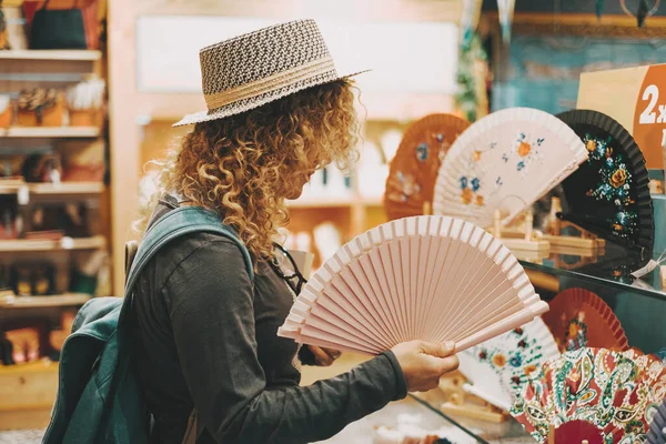 One woman in shopping leisure activity inside a store touching folding fans for heat temperature and climate change earth condition. Concept of female people in shop activity for gifts or pleasure