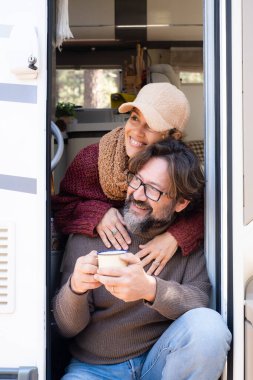 Van life and alternative off grid life and vacation leisure time for happy couple man and woman sitting on the door of their camper van. Travel people and holiday vacation with vehicle rented