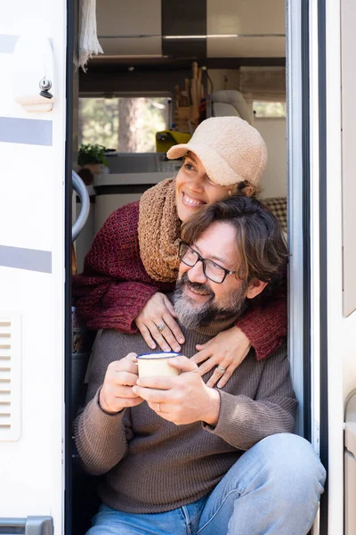 Van life and alternative off grid life and vacation leisure time for happy couple man and woman sitting on the door of their camper van. Travel people and holiday vacation with vehicle rented
