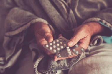 Close up of old man hands with mix of pills medicine to take to heal health. Concept of senior people health lifestyle with pharmacy at home. Flu influenza disease virus contagion. Mature person life