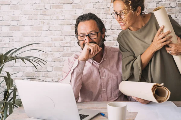 Man and woman team working happy together at the desk looking computer display. Professional worker people enjoy job and business activity. Enjoyed couple using laptop and technology to work modern