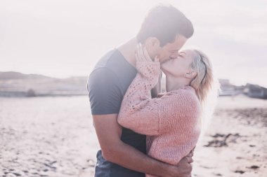 İlişkisi olan bir çift açık havada öpüşüyor. Çıkma ve birlikte tatil kavramı. Genç kız ve erkek güneşin altında romantik bir öpüşme. Yaz tatilinde plajda kucaklaşan iki kişi.