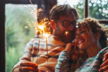 Aşk ve romantik eğlence, kadın ve erkeğin birbirine ateş püskürtücü tutmasıyla evde bir kanepede oturup ilişkinin tadını çıkarması. Mutlu çift için Noel zamanı evde yalnız