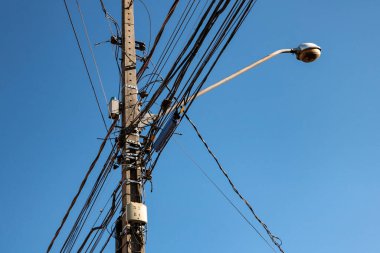 Görüntünün arka planında lamba çubuğu ve mavi gökyüzü ile karışık kablolarla halka açık elektrik ağı direği