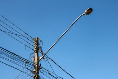 Görüntünün arka planında lamba çubuğu ve mavi gökyüzü ile karışık kablolarla halka açık elektrik ağı direği