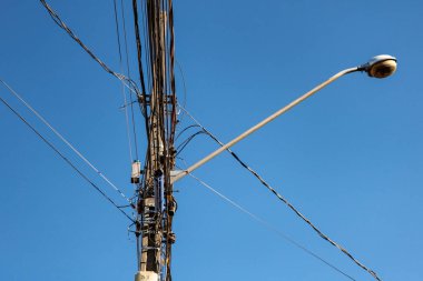 Görüntünün arka planında lamba çubuğu ve mavi gökyüzü ile karışık kablolarla halka açık elektrik ağı direği