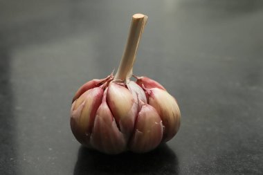 Sarımsak kafalar (Allium sativum) hala ampulde, siyah grantin tabanında koyu bir ışık ve bazı beyaz işaretler var.