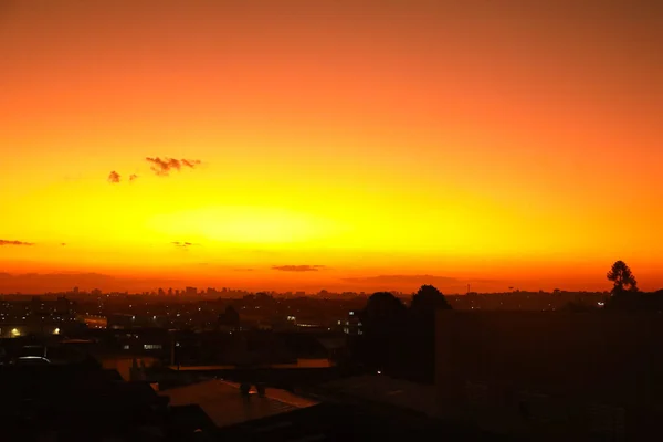 非常にオレンジ色の空で夕日 現時点の特徴 そして画像の基部にいくつかの都市の光 — ストック写真