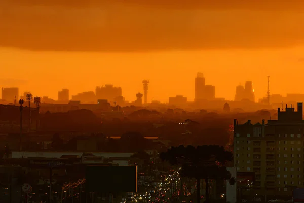 Silhouette of buildings in the central region of Curitiba, capital of Paran, at the end of the day, highlighting the orange color of the twilight and the buildings with a light fog.