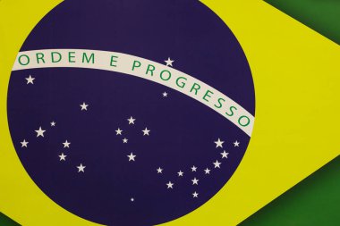Photo of a banner with a piece of the Brazilian flag, which is composed of a green base in the form of a rectangle, superimposed by a yellow diamond and a blue circle, in the middle of which is crossed a white band with the motto Ordem e Progresso