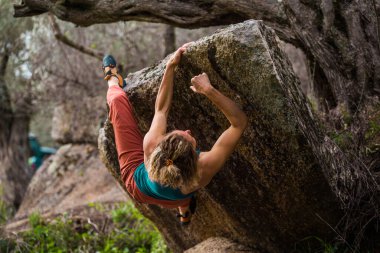 Güzel sporcu kız kaya tırmanışçısı sarkık kayaya tırmanıyor. Doğada kayalık. Spor tırmanışı. Doğadaki uygunluk.