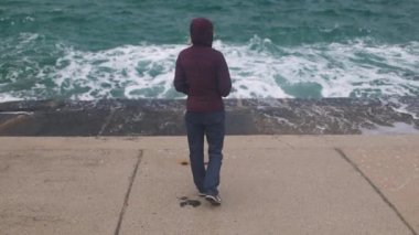 Fırtına sırasında bir kız rıhtımda yürür.