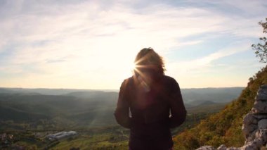 Bir kadın gün batımıyla güzel bir yerde buluşur.
