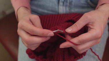 Bir kadın yün iplikten şapka örer..