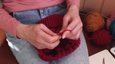 Bir kadın yün iplikten şapka örer..